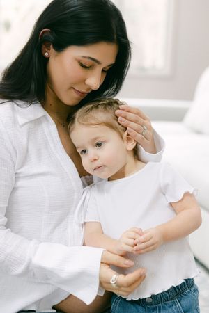 A tender moment captured in white as a parent comforts and embraces a young child.