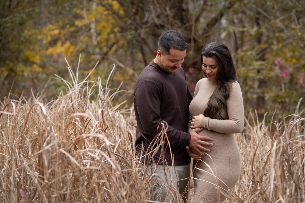 A couple shares an intimate moment together in a field of tall dried grass during autumn.