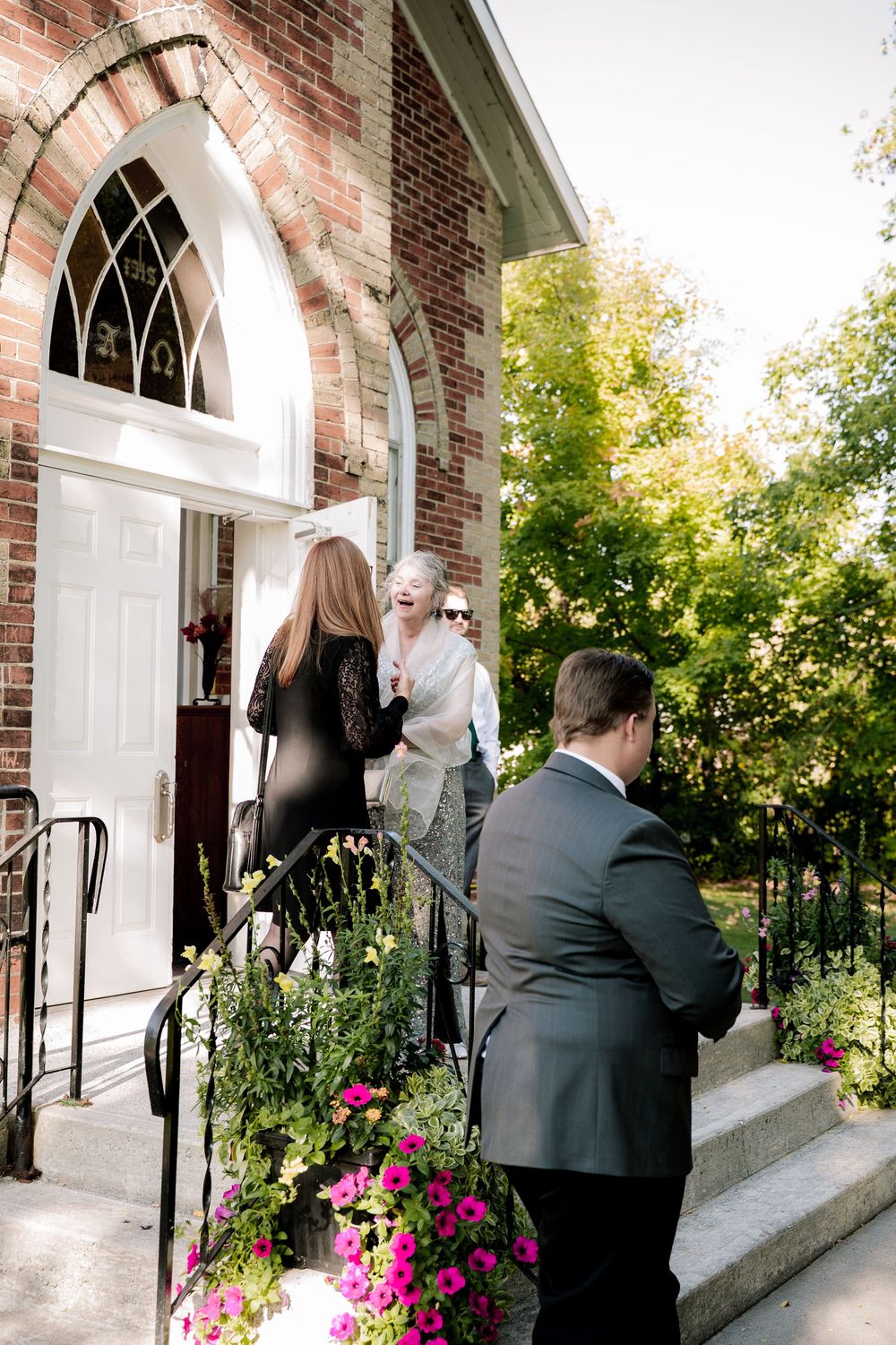 A sequence of four photos showing people entering through white arched doorways of a brick church building with pink flowers.