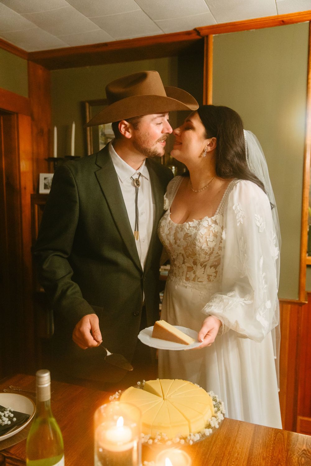 A couple shares an intimate moment during their wedding cake cutting ceremony in a rustic indoor setting.