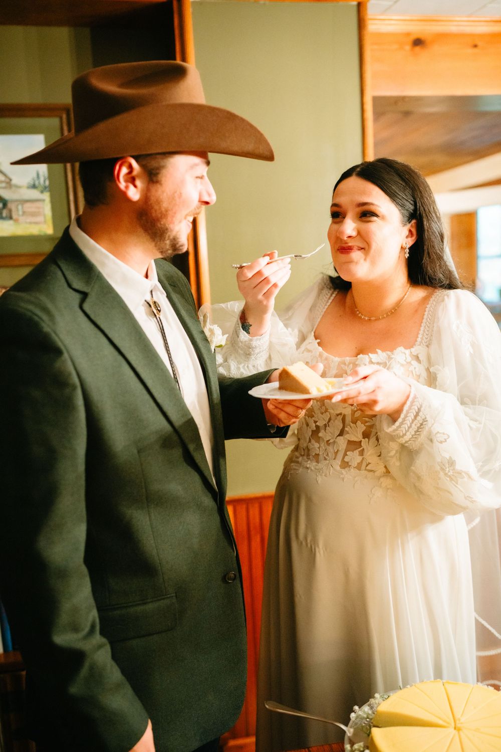 A couple shares a sweet moment during their rustic wedding celebration as they feed each other cake.