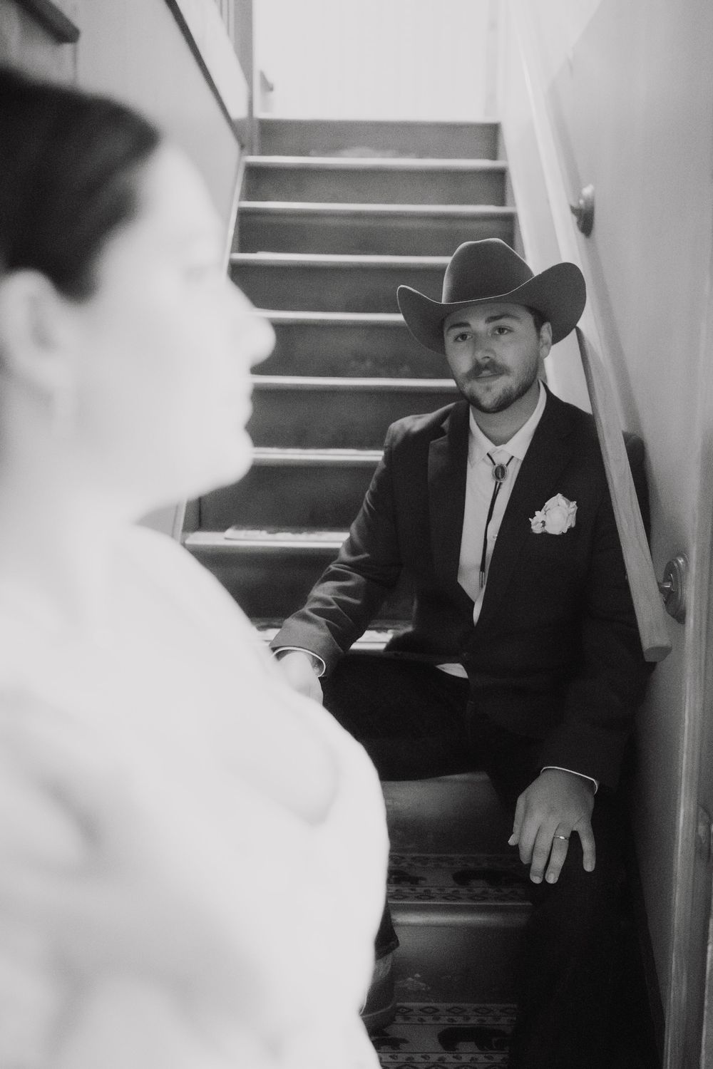 A black and white wedding portrait captured on a staircase with western style elements.