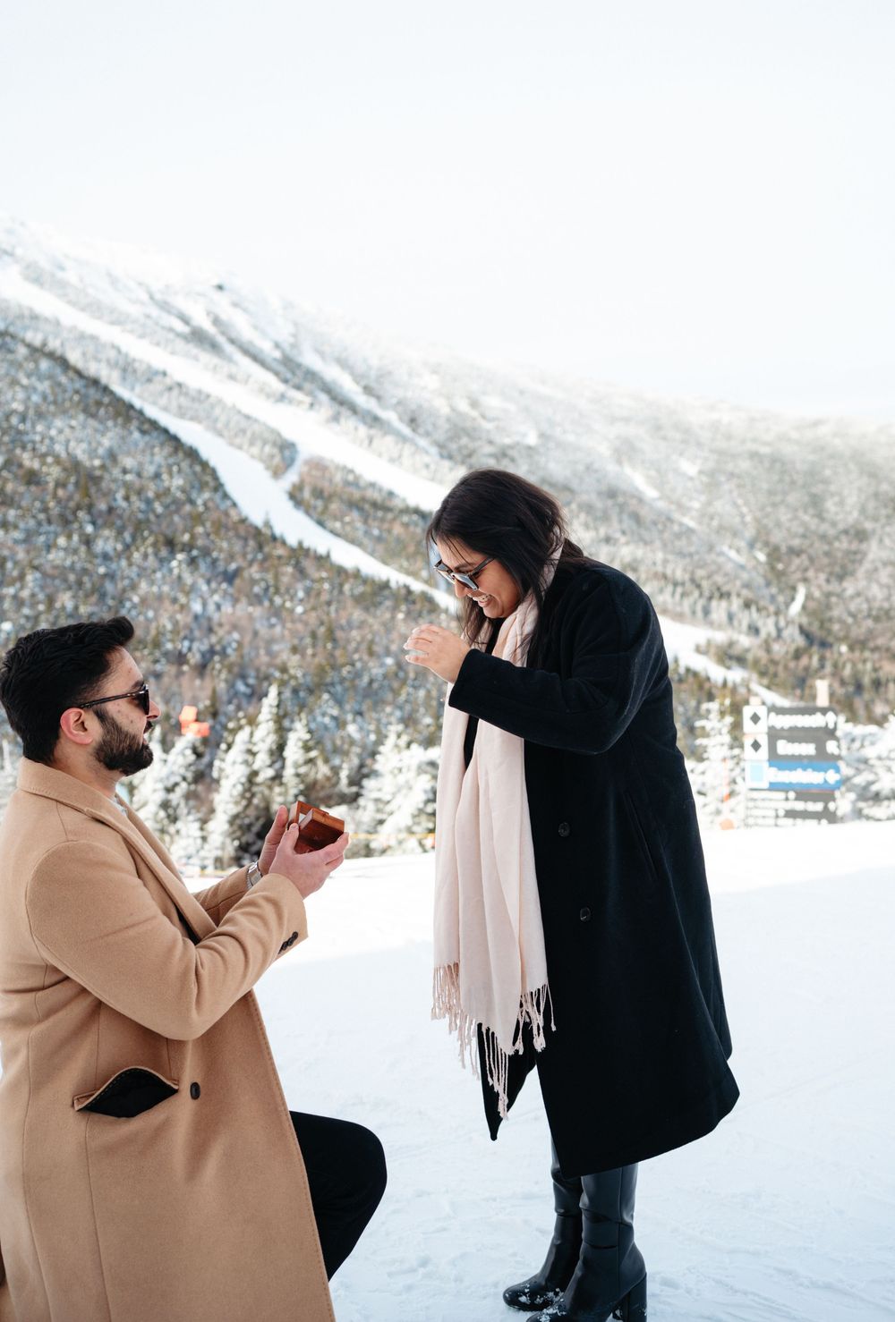 A romantic winter proposal scene unfolds against a snowy mountain backdrop as a couple shares a special moment.