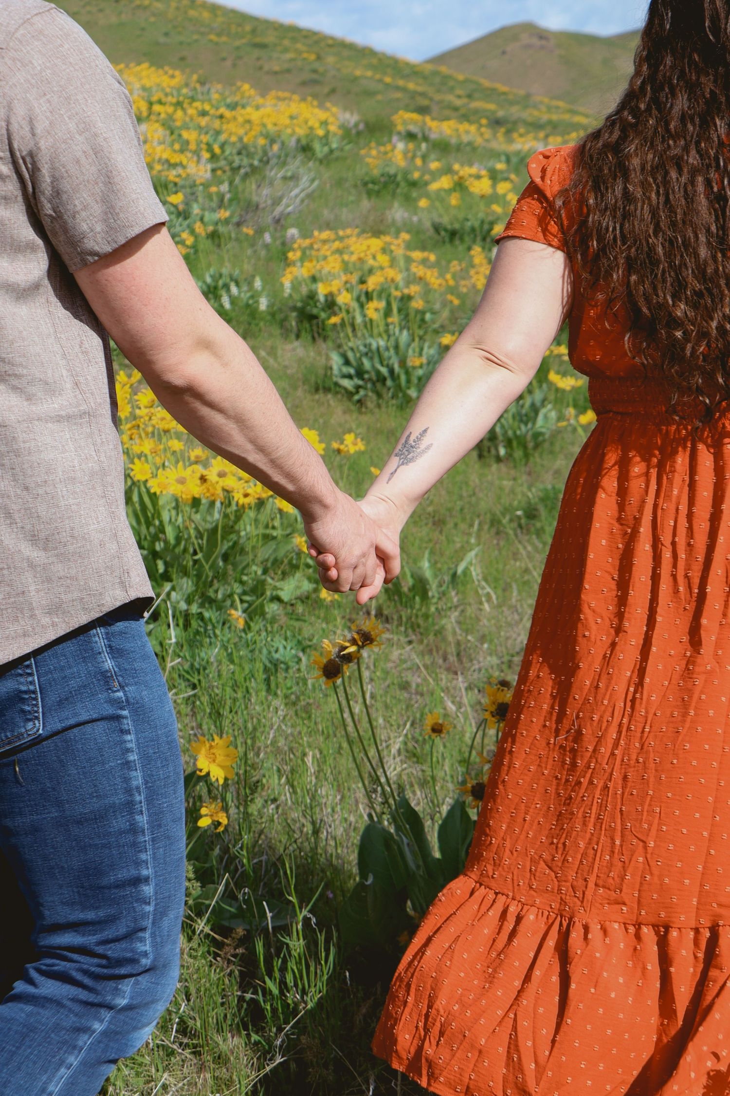 A romantic couple embraces while standing in shallow water with desert hills in the background at sunset.