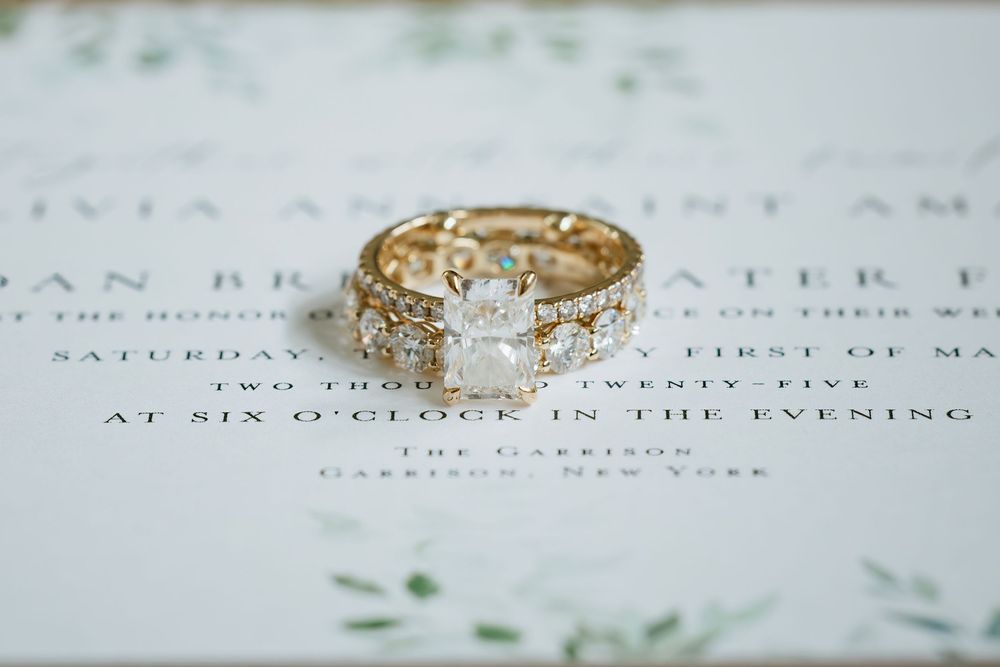 Close-up view of a sparkling diamond engagement ring with intricate details resting on paper.