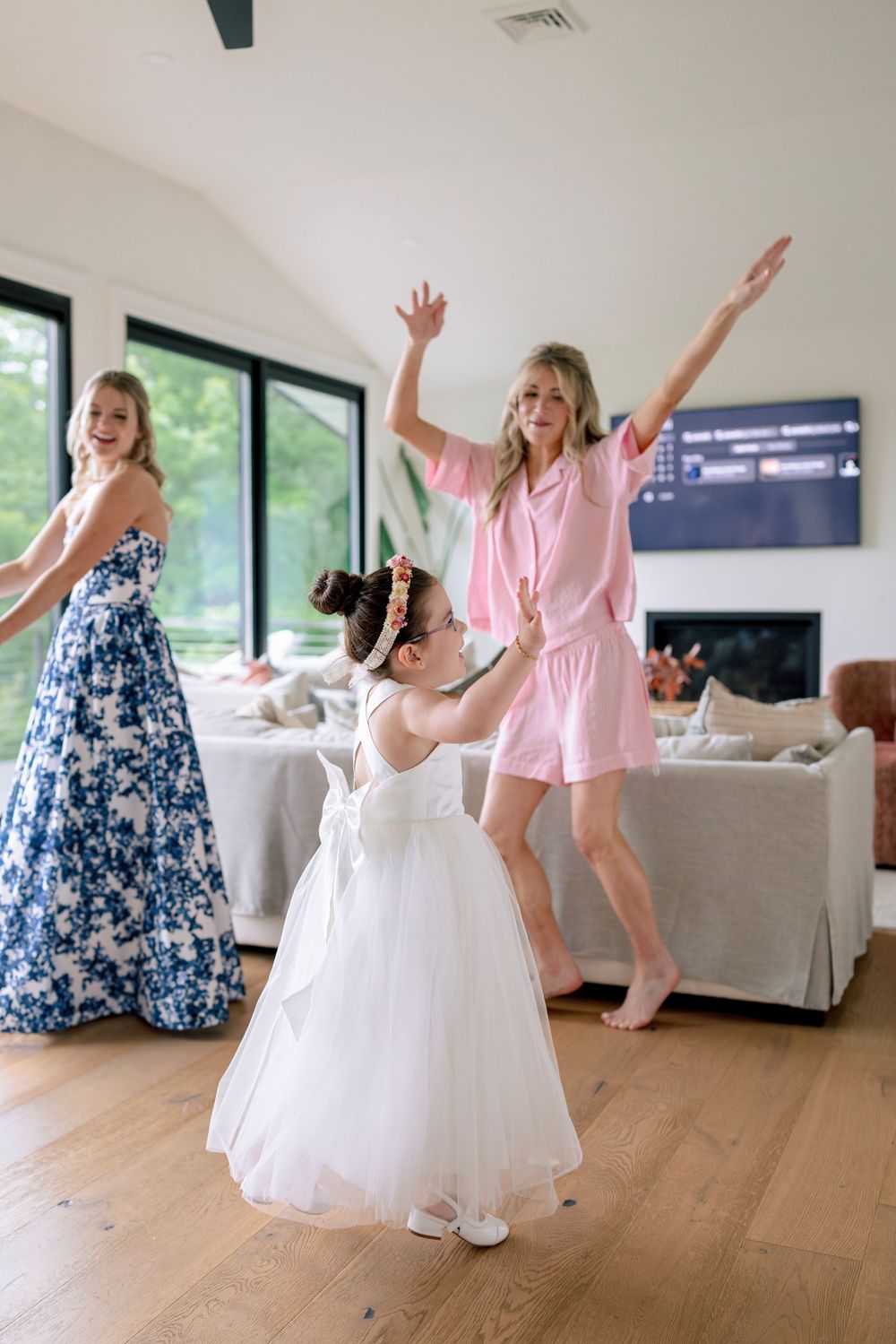 People dancing and celebrating in a bright modern room with hardwood floors and large windows.