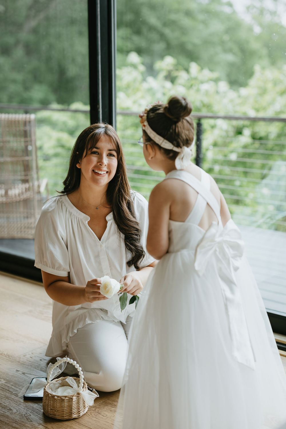 Two people share a joyful moment during wedding preparations in a bright room with large windows.