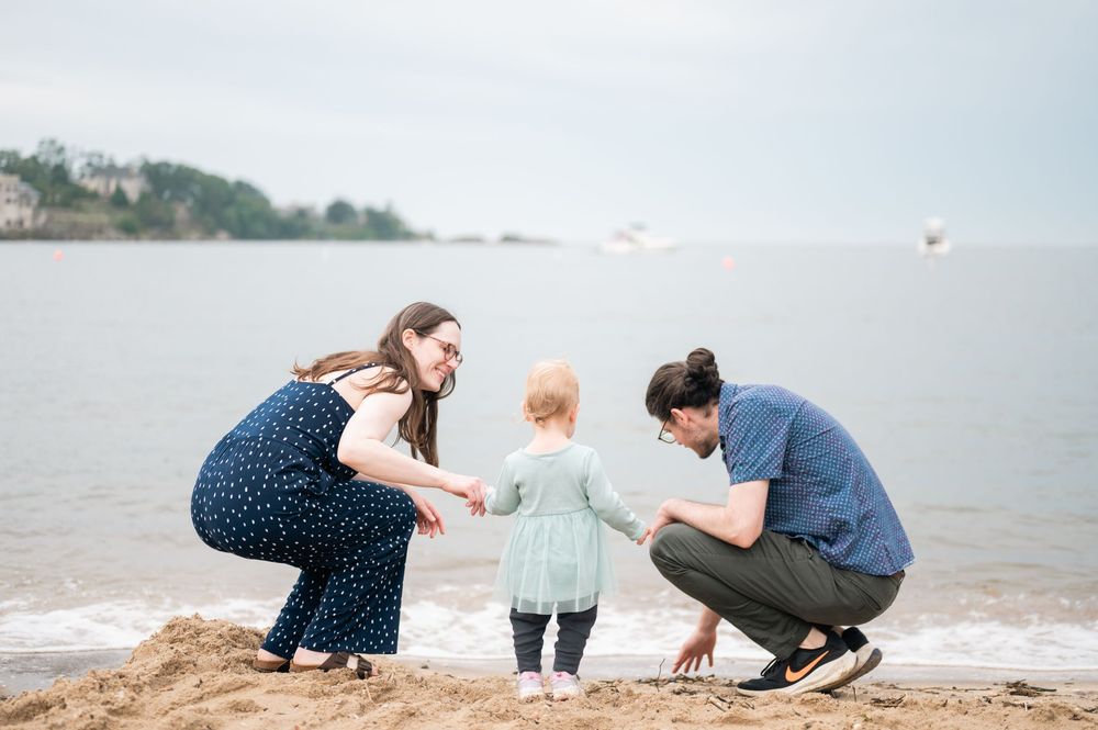 People crouching to explore the beach together on an overcast day. Mini Session Branford point branford Connecticut