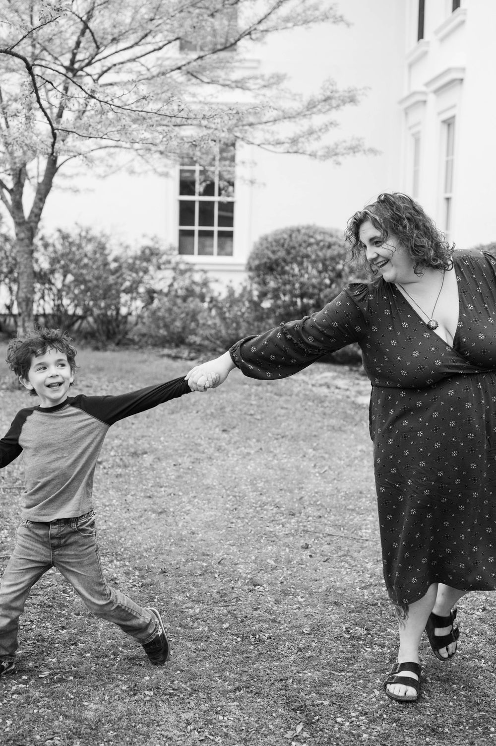 Black and white sequence of playful jumping and movement on a grassy lawn near a house. Cherry Blossom Mini Sessions Branford CT