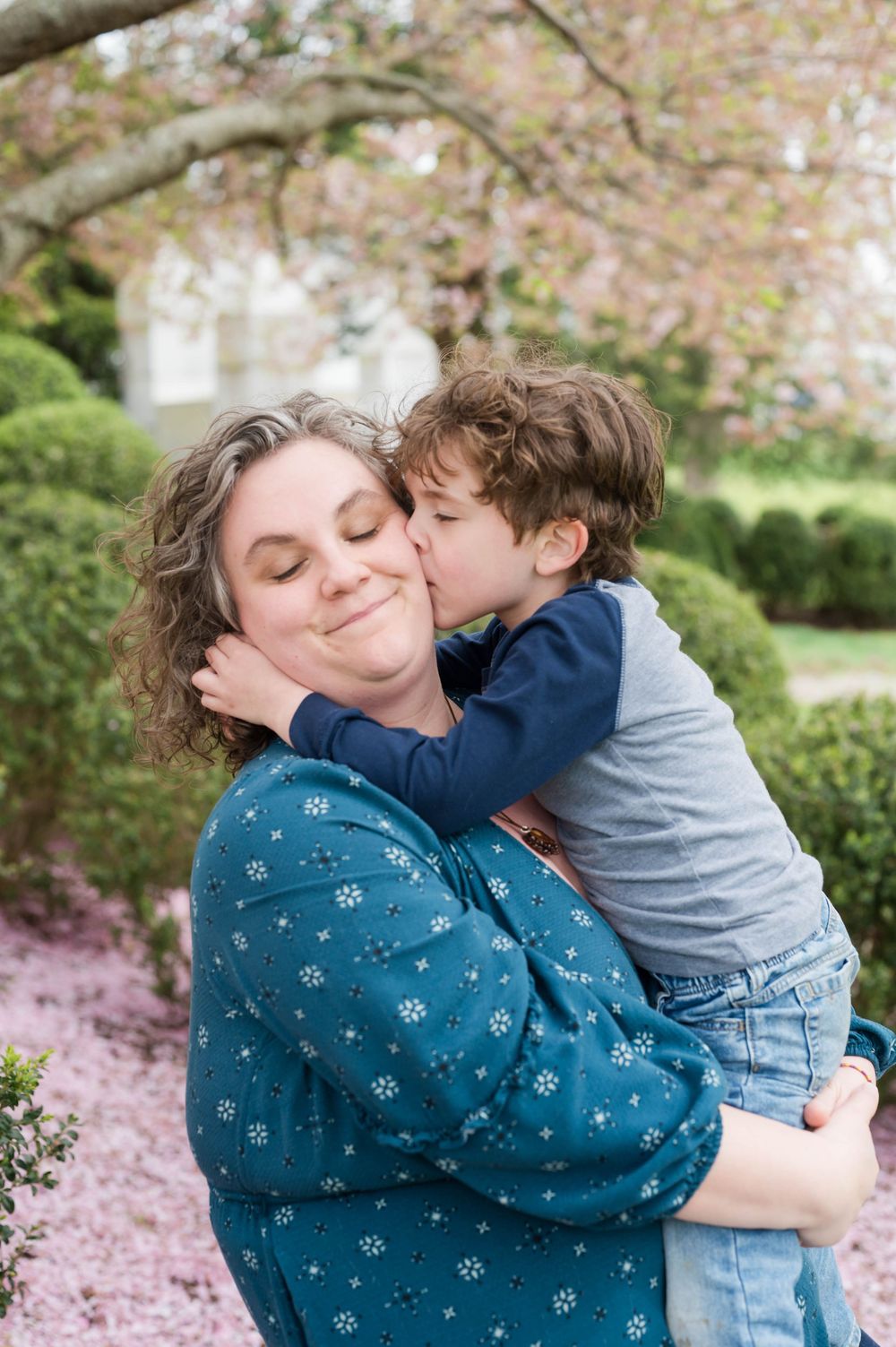 Sweet candid moments shared under blooming spring trees with pink petals. Cherry Blossom Mini Sessions Branford CT