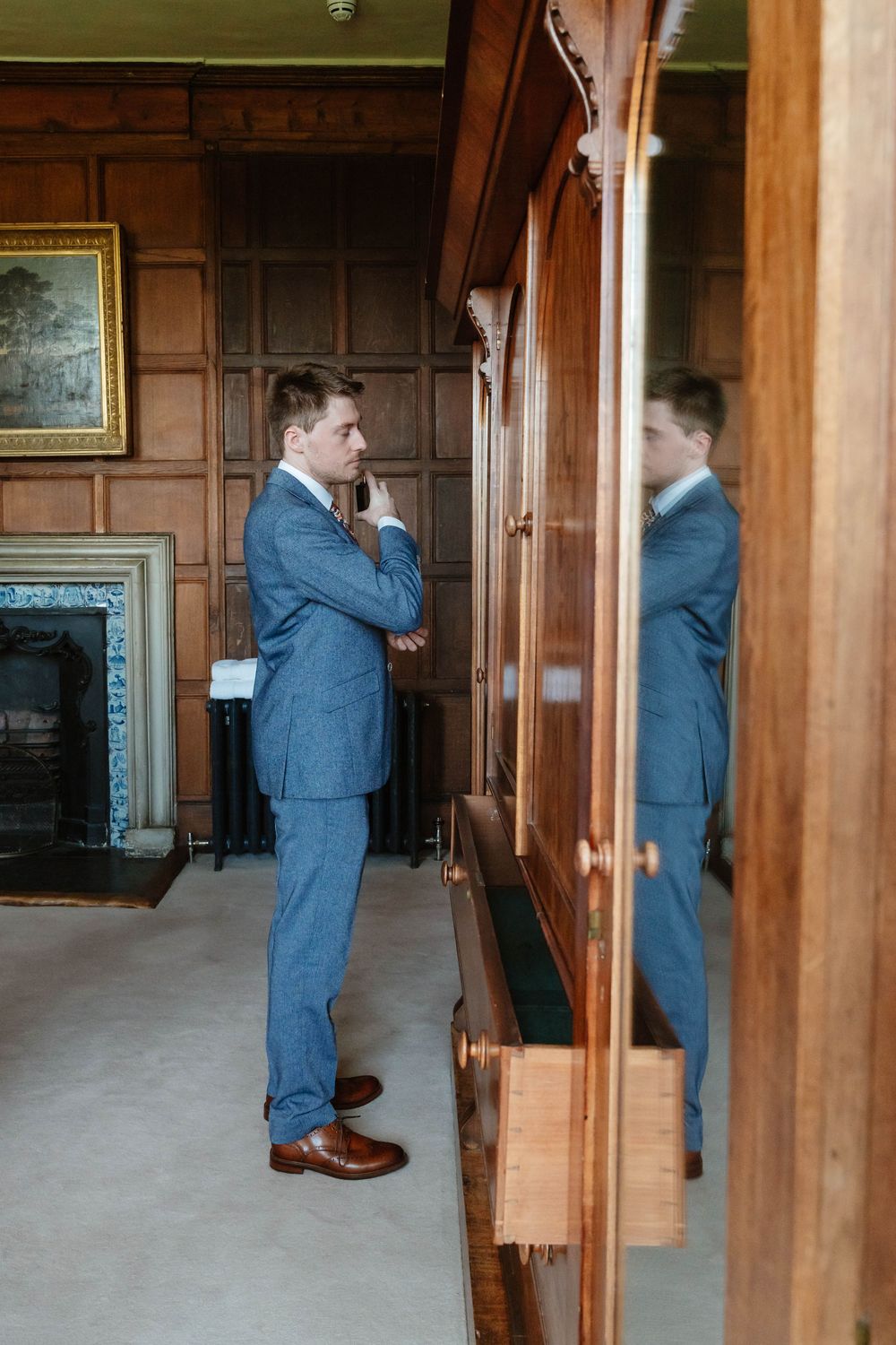 Elmore Court Wedding by Cotswolds Zara Davis Photography in Gloucestershire groom dabbing aftershave in main bedroom