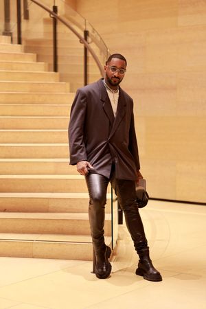 Stylish ensemble featuring an oversized blazer, leather pants and chunky boots on marble stairs with warm lighting.