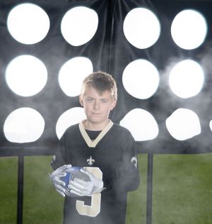 Football player standing under dramatic stadium lights in a dark field atmosphere in Charleston South Carolina