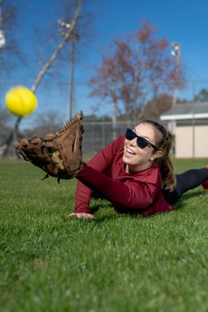 Softball player diving across a grassy field to make a dramatic catch during an action sequence in Charleston South Carolina