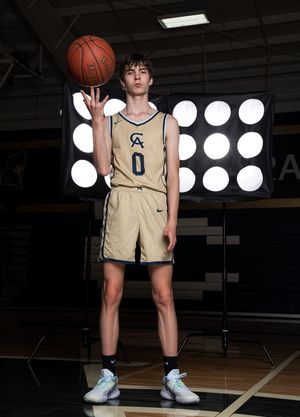 Cathedral Academy basketball player in a beige uniform holding a basketball on an indoor court, photographed from the knees down in Charlest