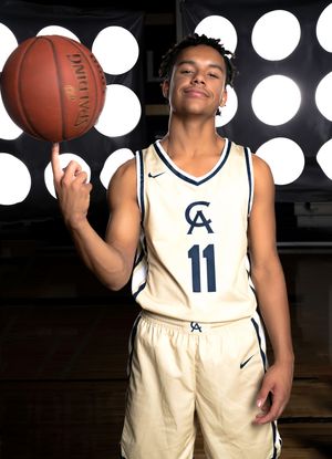 Cathedral Academy basketball player wearing a white number 11 uniform posing with a basketball under dramatic spotlights in Charleston South