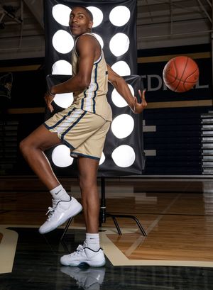 Cathedral Academy basketball player leaping in a dynamic pose on an indoor court with circular studio lights in Charleston South Carolina