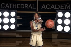 Cathedral Academy basketball player in a gold uniform dribbling a basketball during a game under stadium lights in Charleston South Carolina