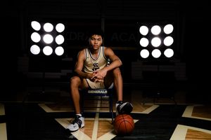 Cathedral Academy basketball player sitting on a chair in a dark gym with stadium lights and a basketball on the floor in Charleston South C