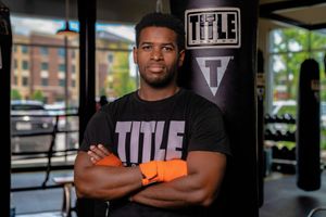 Athlete in black t shirt standing with arms crossed in front of gym equipment at Title Boxing Gym in Summerville South Carolina