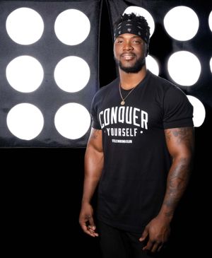 Athlete wearing a Conquer Yourself sleeveless shirt posing with circular lights at Title Boxing Gym in Summerville South Carolina