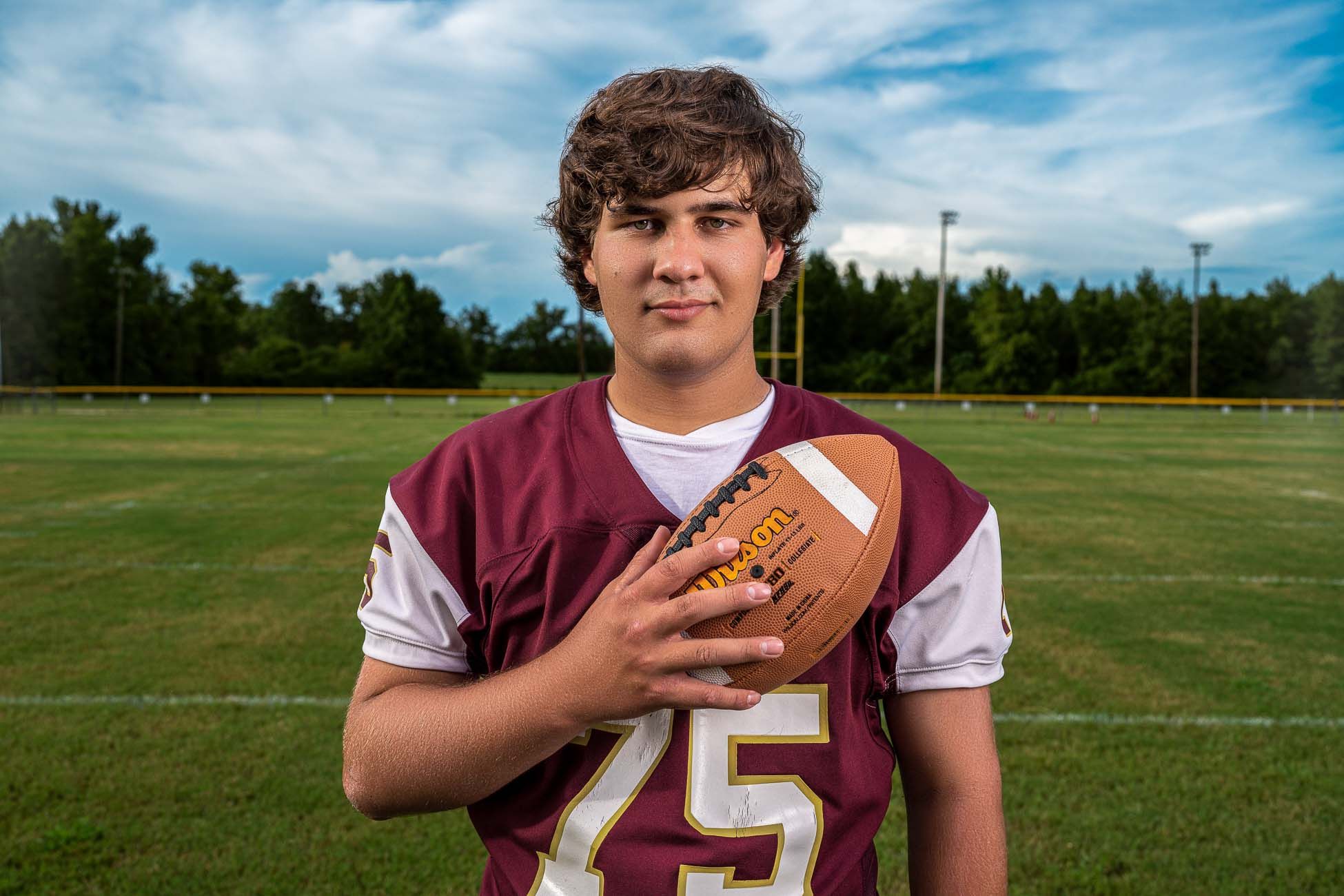 Dorchester Academy football player portrait holding a football on a grassy field in St George SC