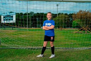 Cathedral Academy soccer player standing in front of a goal net on a grass field wearing a blue jersey in Charleston South Carolina