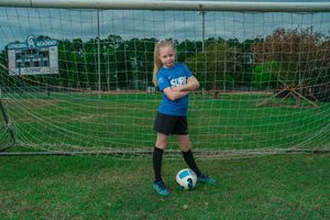 Cathedral Academy soccer player kicking a ball into the goal during a practice shot sequence on a grass field in Charleston South Carolina