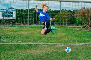 Cathedral Academy soccer player leaping in front of a goal with a ball on the field during an action shot in Charleston South Carolina