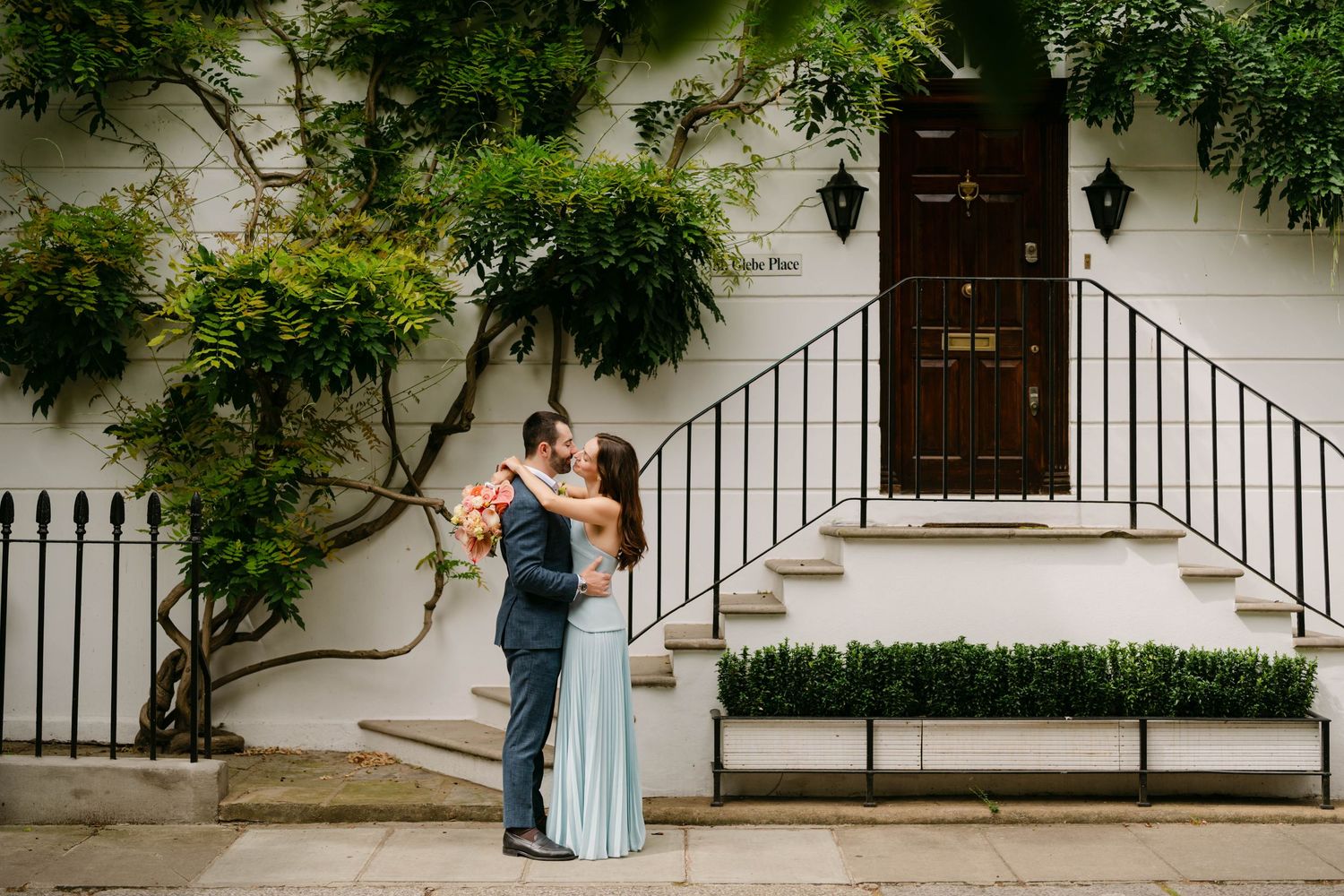 A scenic garden pathway lined with manicured hedges and cypress trees leads through an elegant Italian-style landscape.