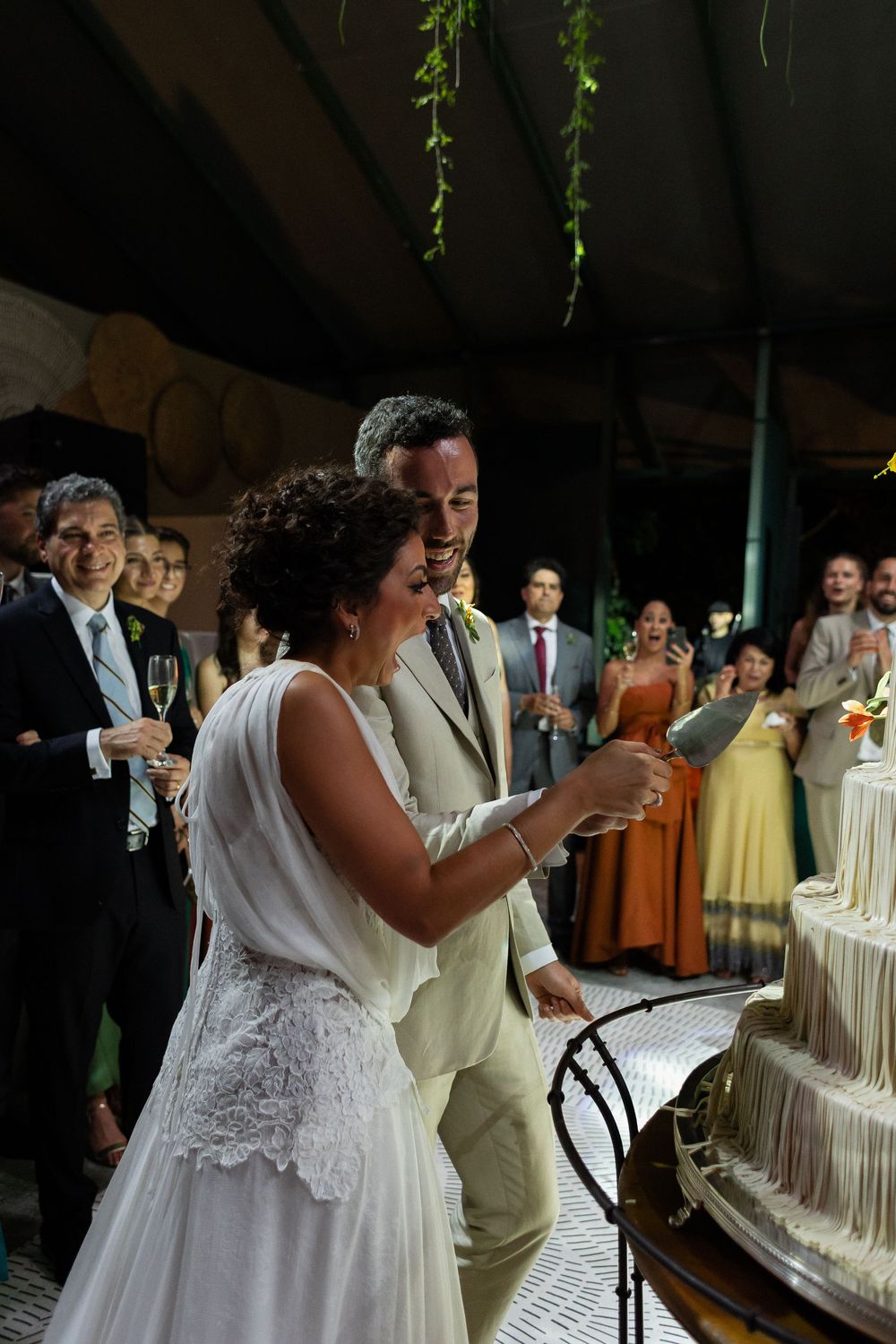 Newlyweds share a joyful moment while cutting their elegant white wedding cake together at their reception.