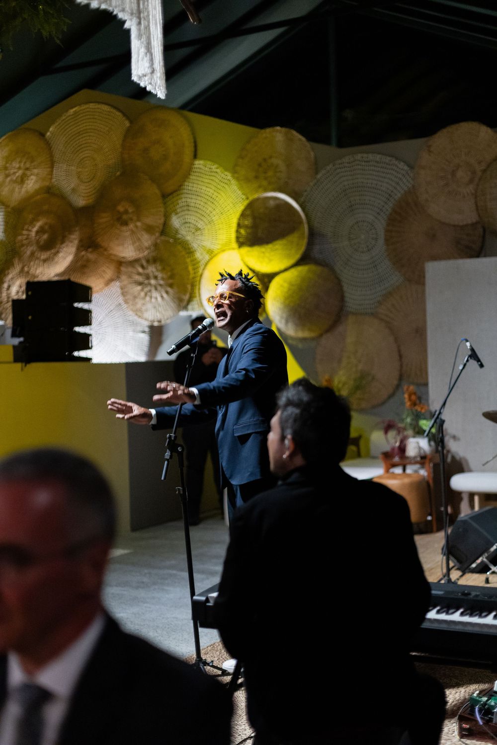 Musicians perform at a wedding reception with dramatic yellow lighting and decorative paper lanterns.