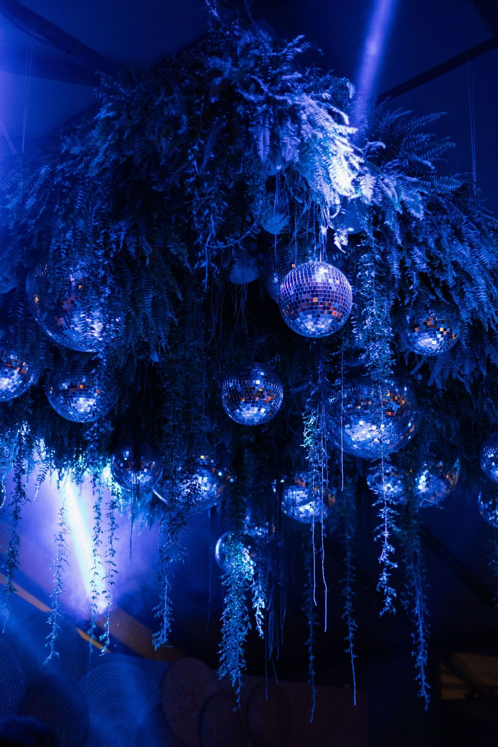 Blue-lit disco balls and icicle lights create a magical winter wonderland ceiling display.