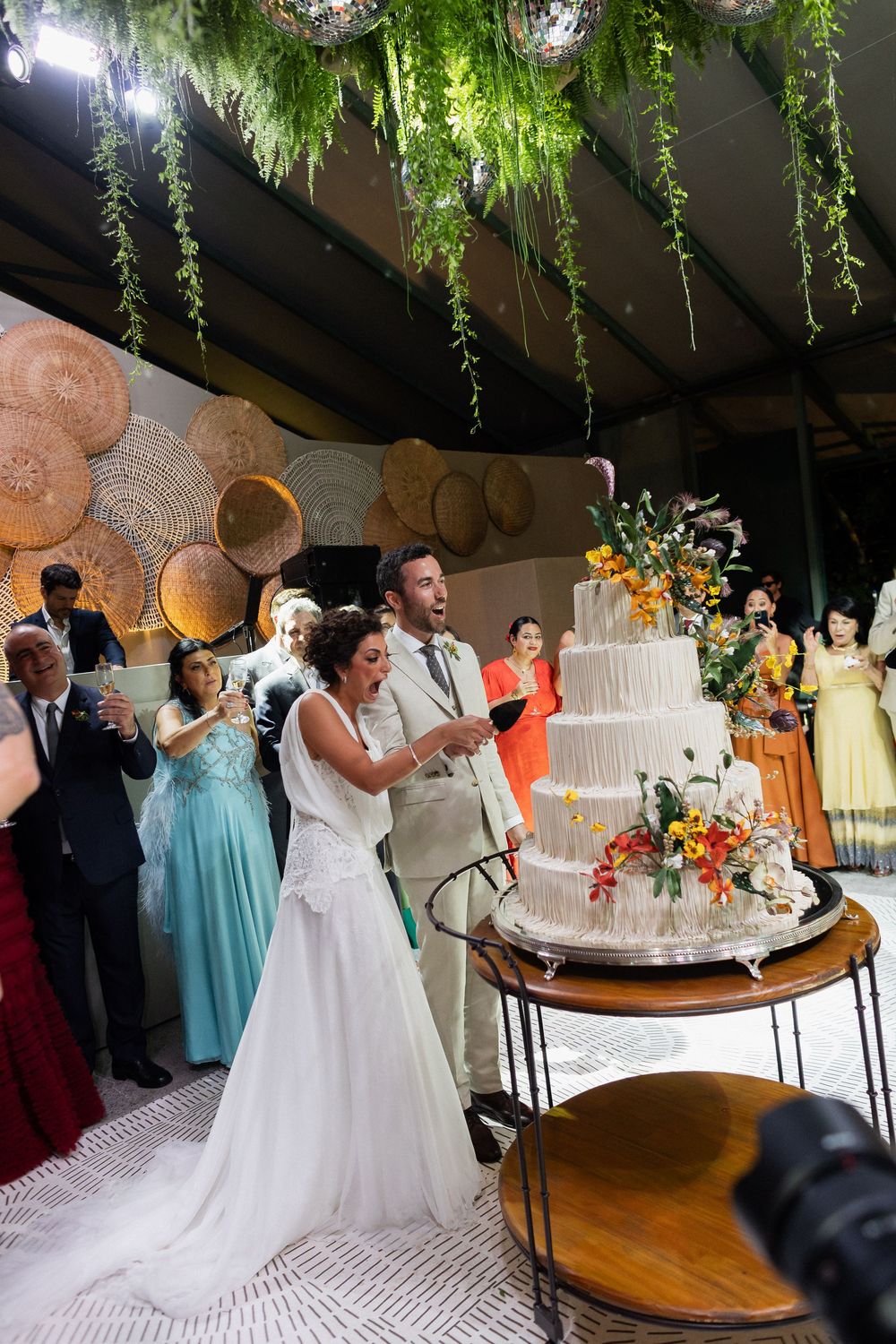 Wedding couple shares their first dance under hanging greenery and crystal chandeliers at an elegant reception venue.