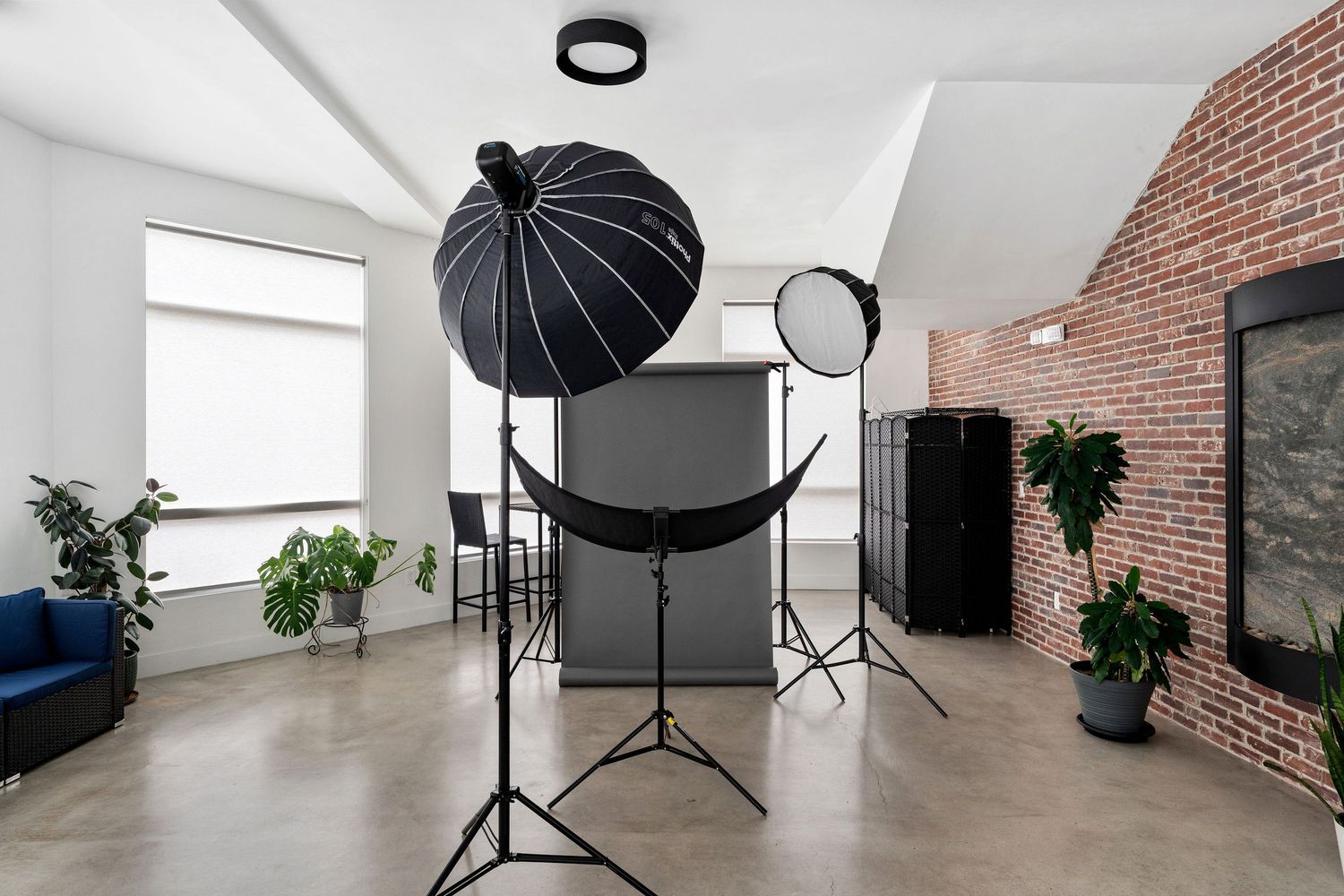 Professional photo studio setup with lighting equipment, soft boxes and backdrop and reflectors in a modern space with brick walls.