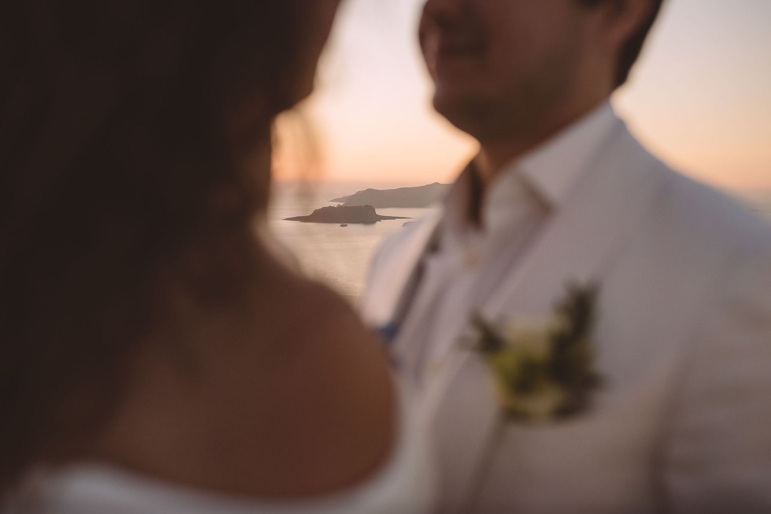 A couple shares an intimate moment during their outdoor destination wedding at sunset in Santorini.