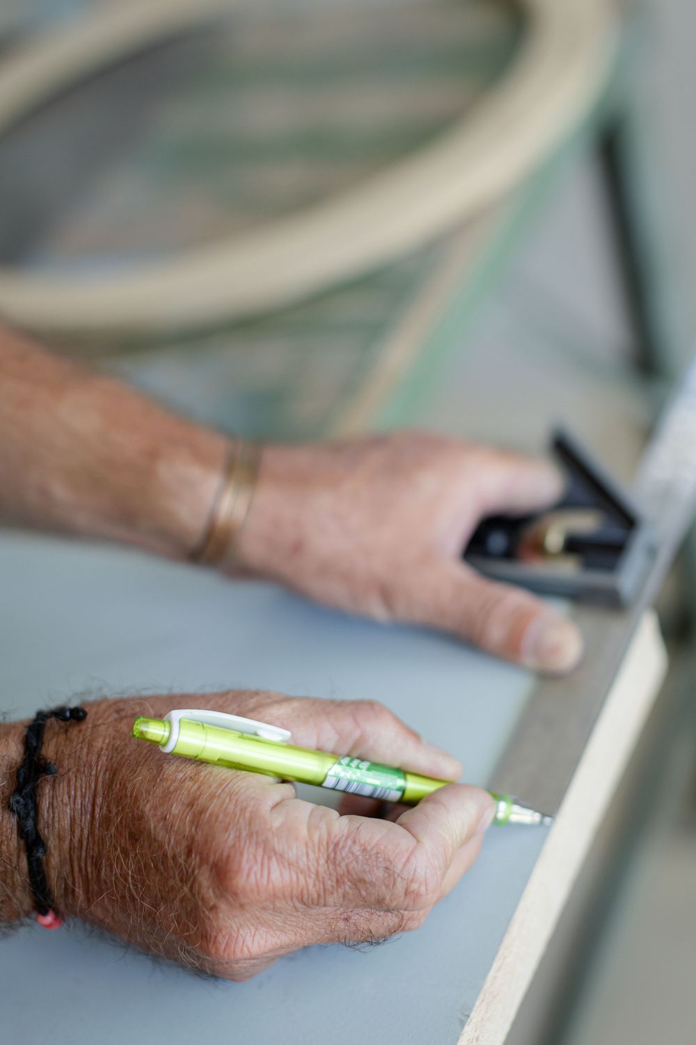Close-up of hands using measuring tools and markers on construction materials.