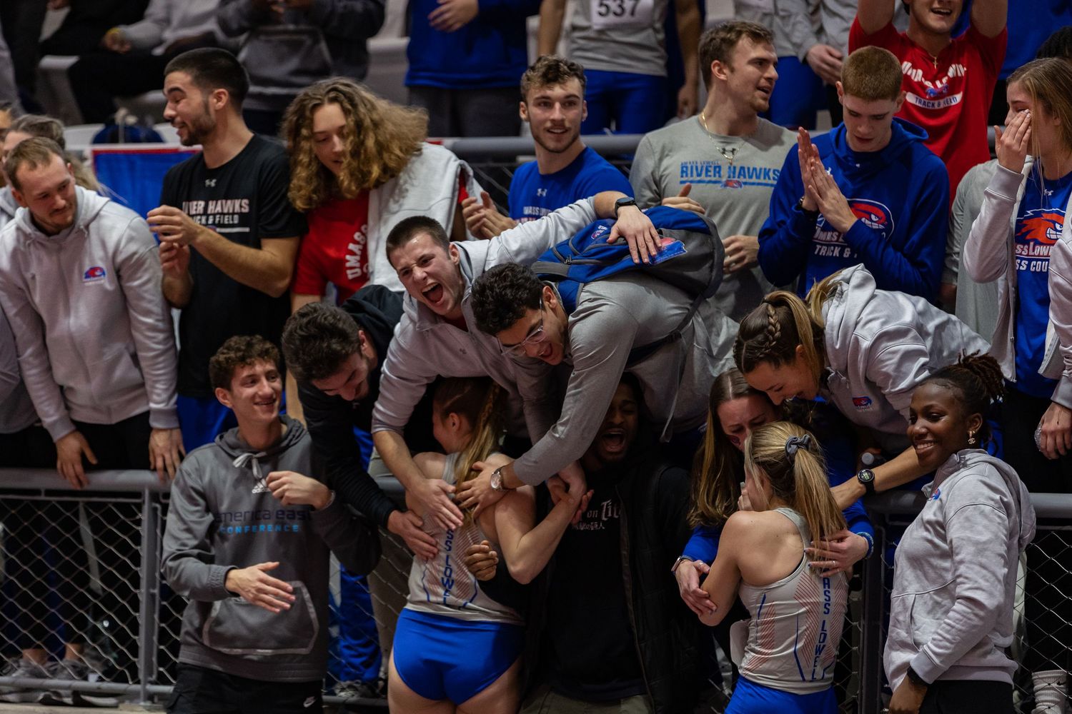 Excited crowd of spectators cheering at indoor sporting event.