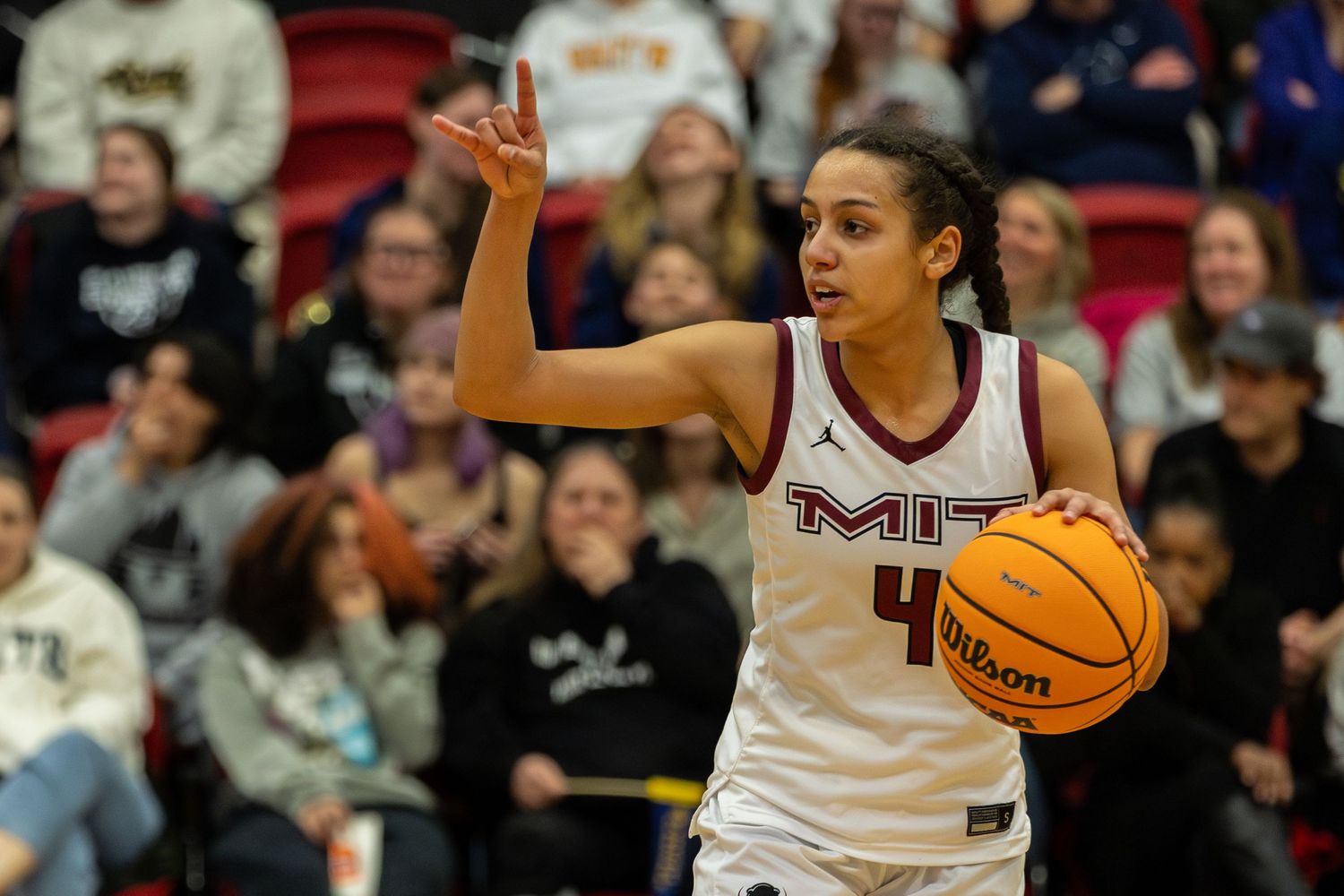Basketball player dribbles while calling a play during an intense game at MIT.