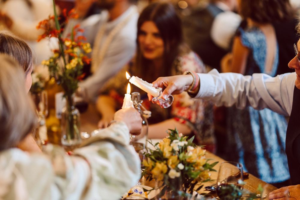 A festive wedding reception table decorated with elegant floral centerpieces and glowing candlelight.
