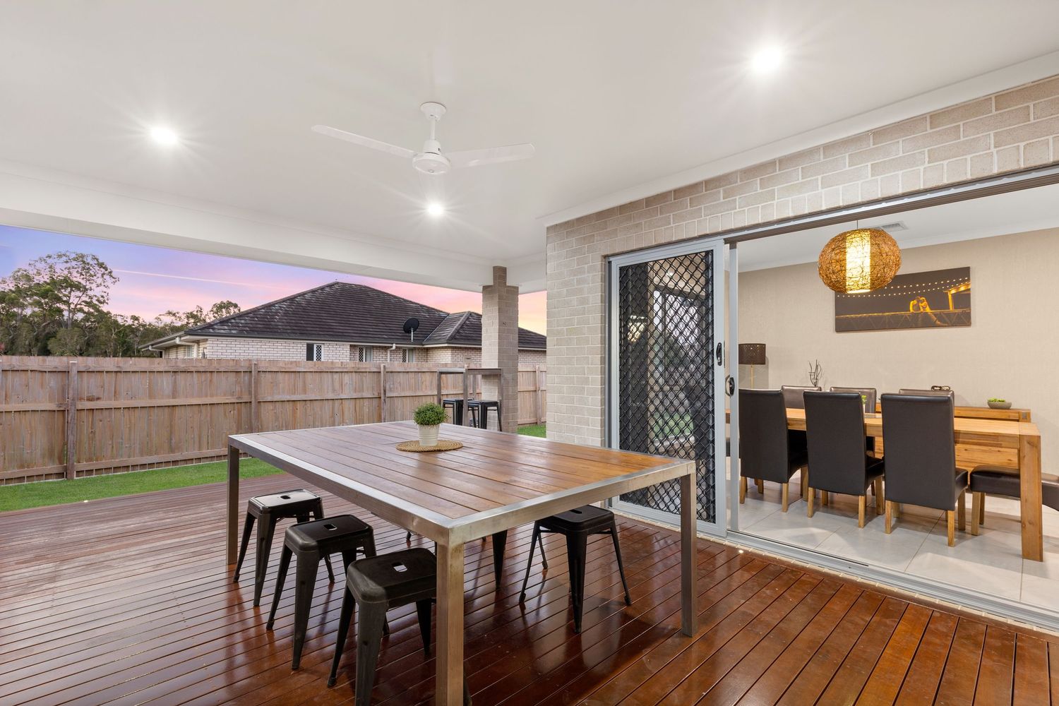 Outdoor timber deck dining area with ceiling fan and sliding doors to interior dining room.