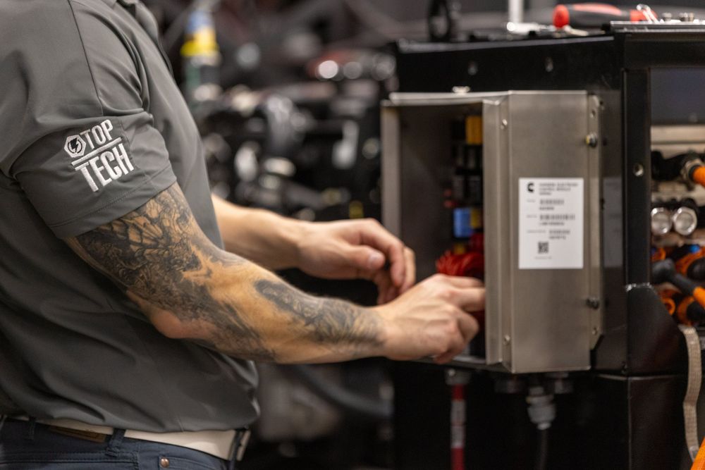 A tattooed person works on repairing or maintaining equipment in a workshop setting.
