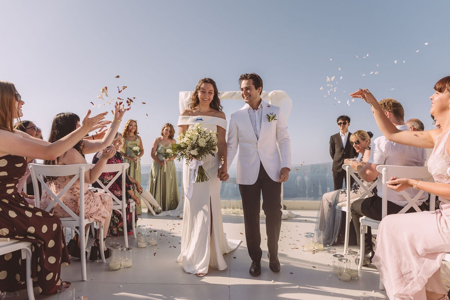 Destination wedding couple exiting Santorini ceremony at El Viento while guests throw confetti.