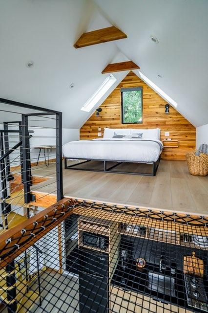 Cozy loft bedroom with wood paneling and black safety netting features a comfortable bed and natural lighting from skylights.
