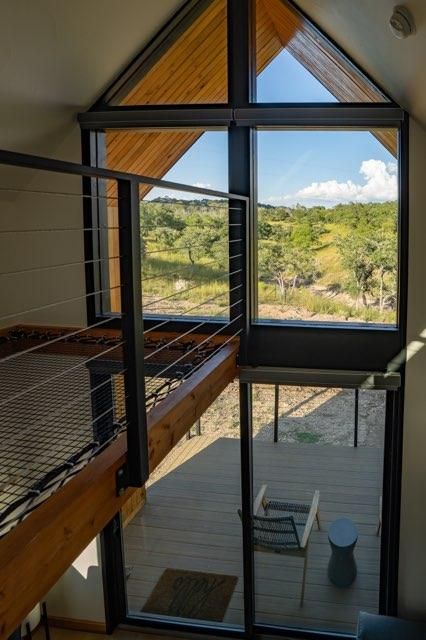 Modern tiny house interior with large windows showcasing scenic mountain views and a suspended loft space.