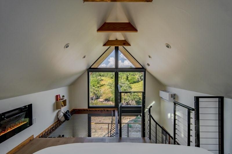 Modern interior staircase with black metal railings and white walls leads to an open loft area with natural lighting.