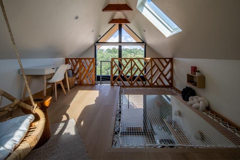 Sunlight streams through skylights in a modern attic loft space with wooden beams and white walls.