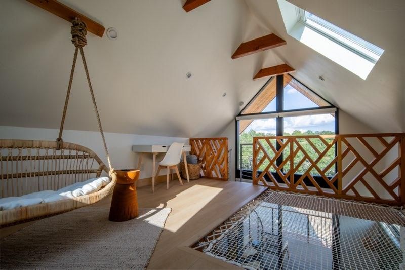 Interior view of a modern loft space with exposed wooden beams and skylights letting in natural light.
