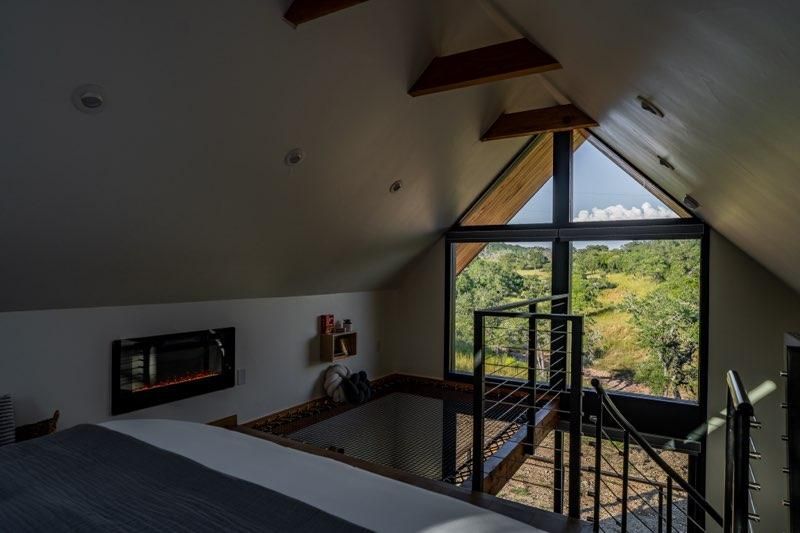 Spacious loft interior with exposed wooden beams, large windows, and natural light illuminating the space.