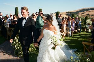 Elegant outdoor wedding ceremony with guests seated on lawn surrounded by cypress trees and countryside views.
